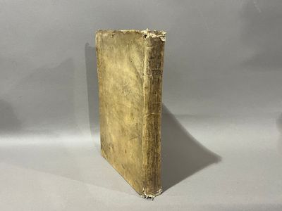 un vieux livre posé sur une table blanche à côté d'un mur blanc
