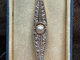 an antique silver spoon with a pearl in it sitting in a box