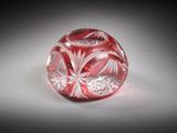 une image représentant un objet en verre rouge et blanc posé sur une surface blanche