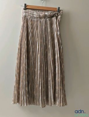the skirt is hanging on a hanger against a wall