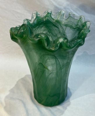 un vase vert posé sur une surface blanche
