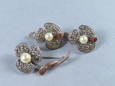 trois bijoux en argent et en perles posés sur un fond bleu