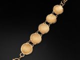 a close up of a gold bracelet on a black background