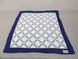 a white and blue blanket sitting on top of a bed