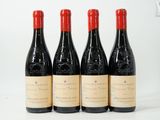 quatre bouteilles de vin rouge sont alignées sur une surface blanche