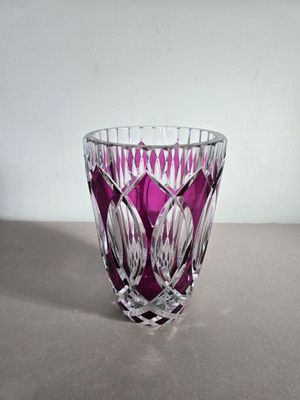 un vase violet posé sur une table, avec un mur blanc en arrière-plan