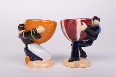 two figurines of a man and a woman holding a cup