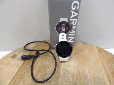 une montre Garmin posée sur une table en bois à côté d'une boîte