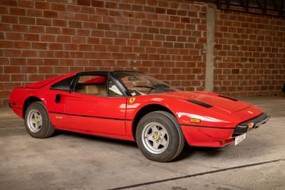 a red sports car parked in front of a brick wall