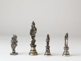 a group of four silver chess pieces on a white surface