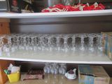 many empty wine glasses on a shelf in the kitchen