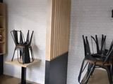 tables and chairs in a room with a brick wall and a clock on the wall