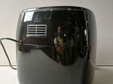 a black toaster sitting on a counter with a reflection of a man in the background