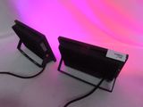 two black and white lights on a white surface with a pink background