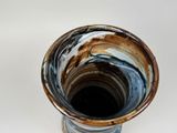 a brown and blue vase sitting on a white surface