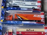 Plusieurs camions miniatures sont alignés dans des sacs en plastique, posés par terre