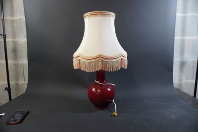 une lampe rouge avec un abat-jour blanc posée sur une table
