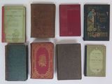 several old books are lined up on a white surface