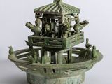 une statue verte représentant un bateau avec des personnes à bord