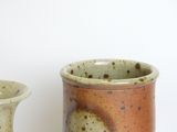 two small vases sitting next to each other on a table