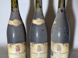 three bottles of wine sitting on a table with a white wall in the background