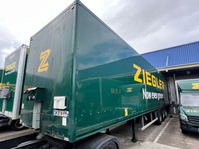 a green semi truck that is parked in front of a building