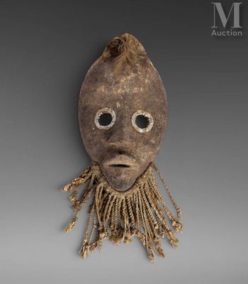 a wooden mask with long hair and eyes on a gray background
