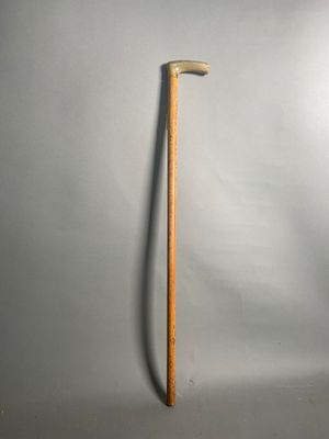 un vieux bâton en bois appuyé contre un mur blanc
