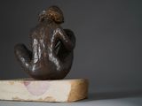 a small statue of a person sitting on a piece of wood