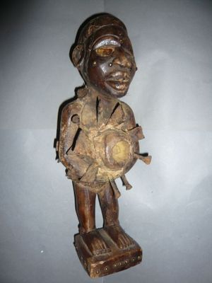 une vieille statue en bois représentant un homme coiffé d'un chapeau et tenant une balle