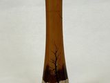 un vase en verre orné d'un arbre, posé sur une surface blanche
