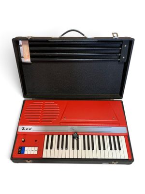 a red keyboard in a black case on a white surface