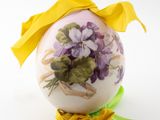 a decorated easter egg with flowers and a yellow ribbon