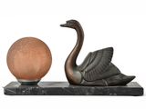 une statue représentant un cygne et une boule, posée sur un socle en marbre