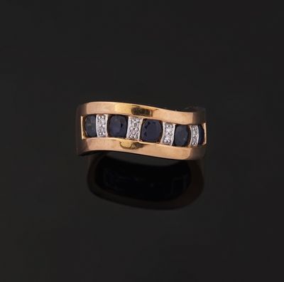 a gold ring with sapphires and diamonds on a black surface