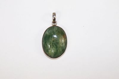 un gros plan d'un pendentif en pierre verte posé sur une surface blanche