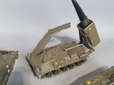 four toy army tanks and a missile on a white surface