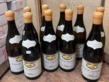 six bottles of wine are lined up on a wooden table