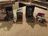 three old cameras sitting on a table next to each other