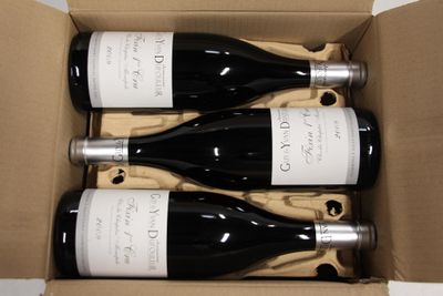 three bottles of wine are in a cardboard box on a table