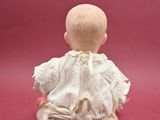a small figurine of a baby sitting on a pink surface