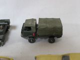 three toy army vehicles are lined up on a white surface