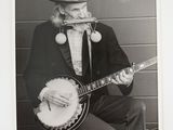 black and white photograph of a man with a beard playing a banjo
