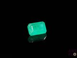 a close up of a green emerald on a black surface