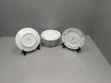 three white and gold china plates on a white table