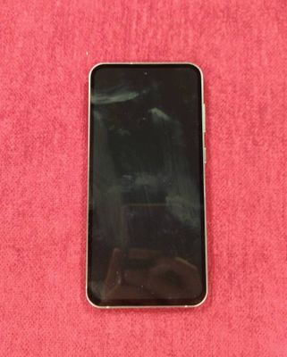 une photo d'un téléphone portable noir posé sur une surface rose