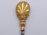a gold spoon with a gold handle on a white surface