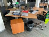 a desk with two computers and a trash can on it