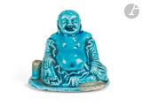 une petite statue bleue représentant un Bouddha souriant, assis sur un rocher