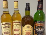 quatre bouteilles d'alcool sont alignées sur une table